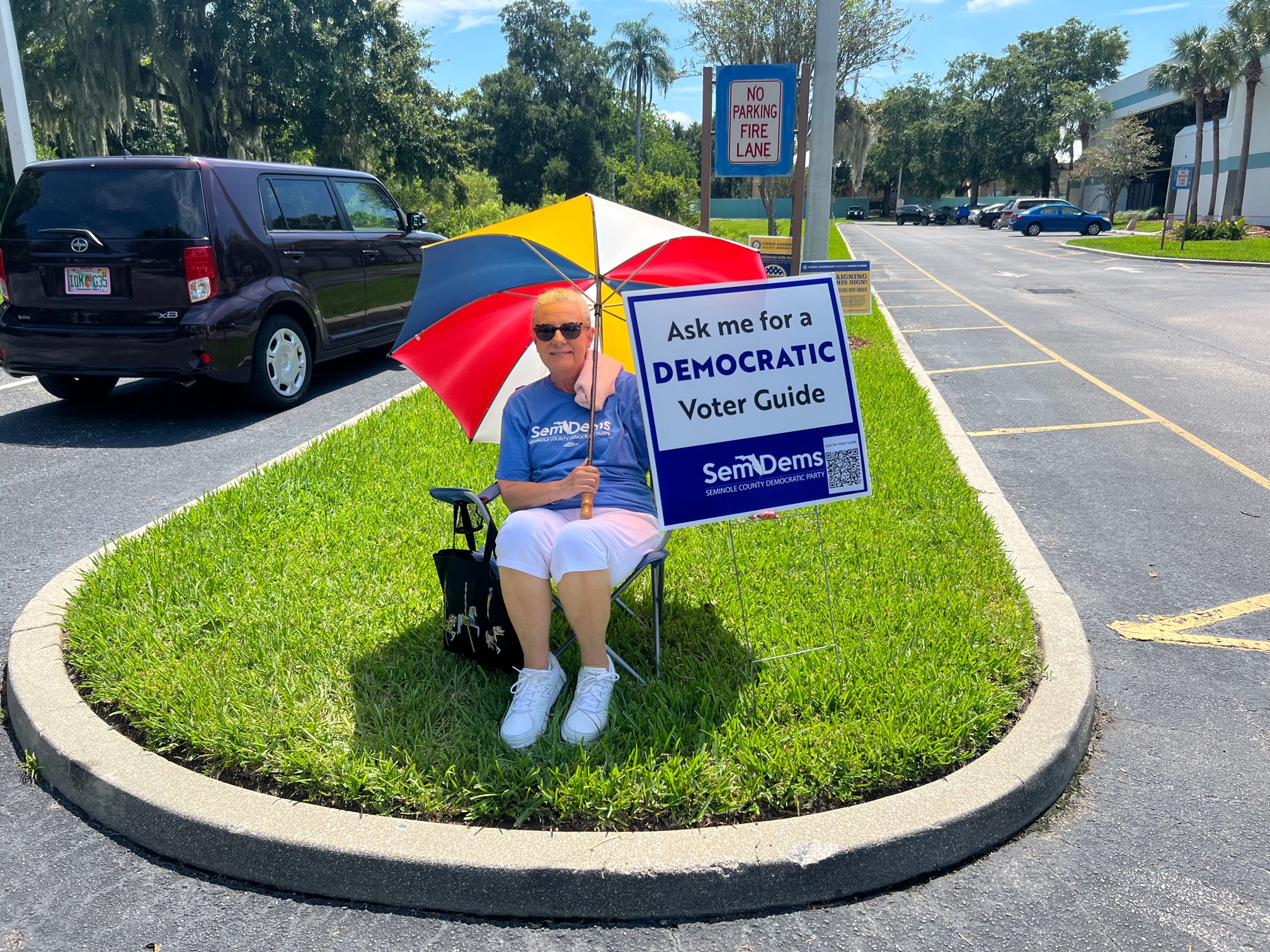 Volunteer with Umbrella Holding Ask Me for a Democratic Voter Guide sign